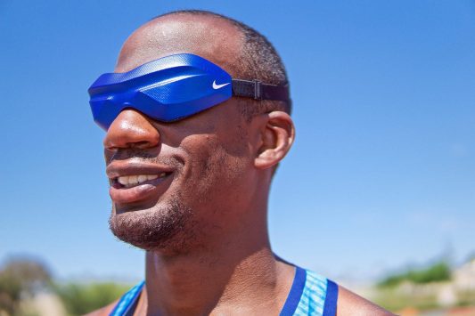 Athlete wearing blue Nike eye mask under a clear sky.