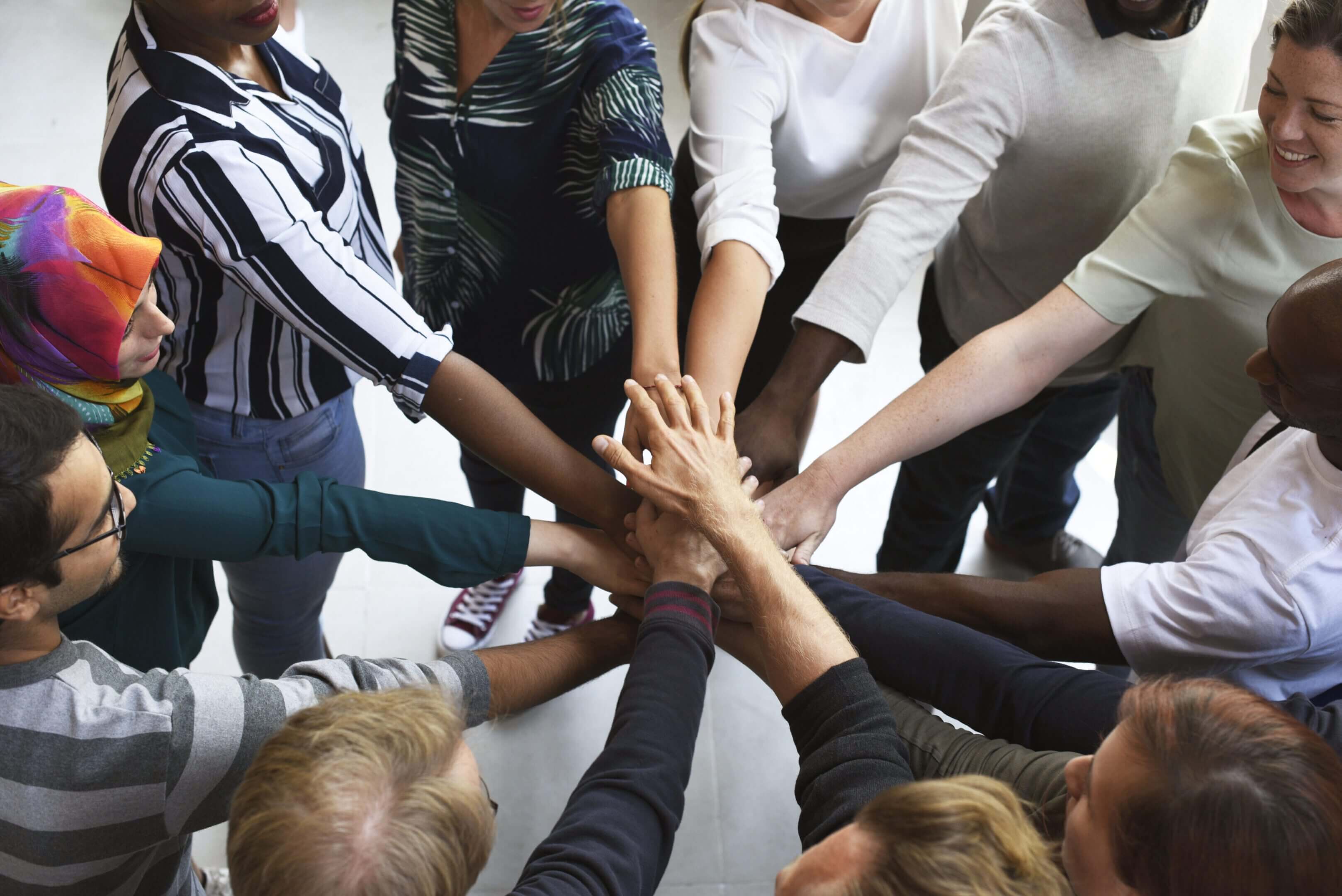 Diverse team joining hands in unity and collaboration.