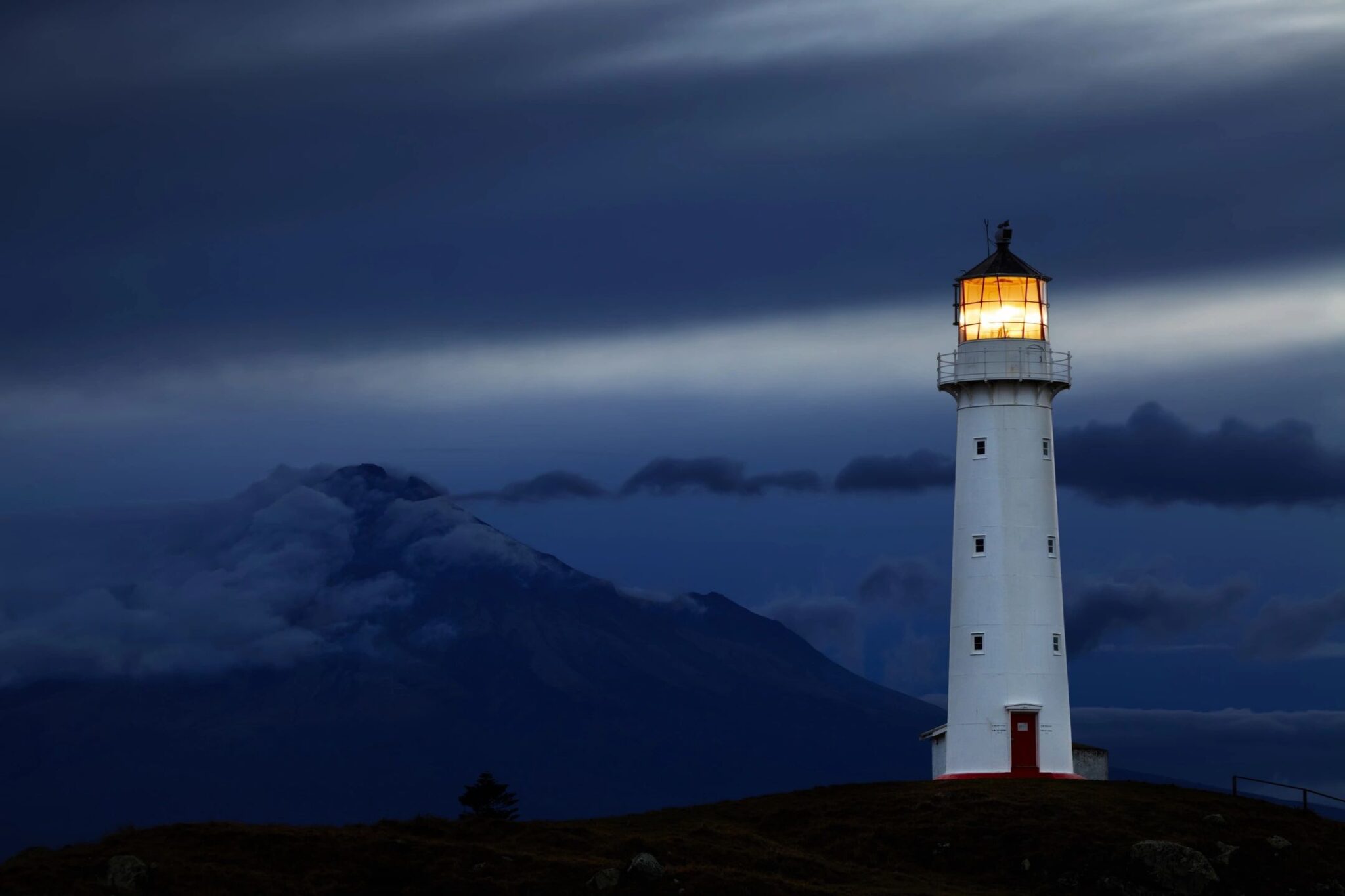 A lighthouse shining brightly against a dark, cloudy sky.