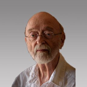 Portrait of an elderly man with glasses and a white beard against a neutral background.