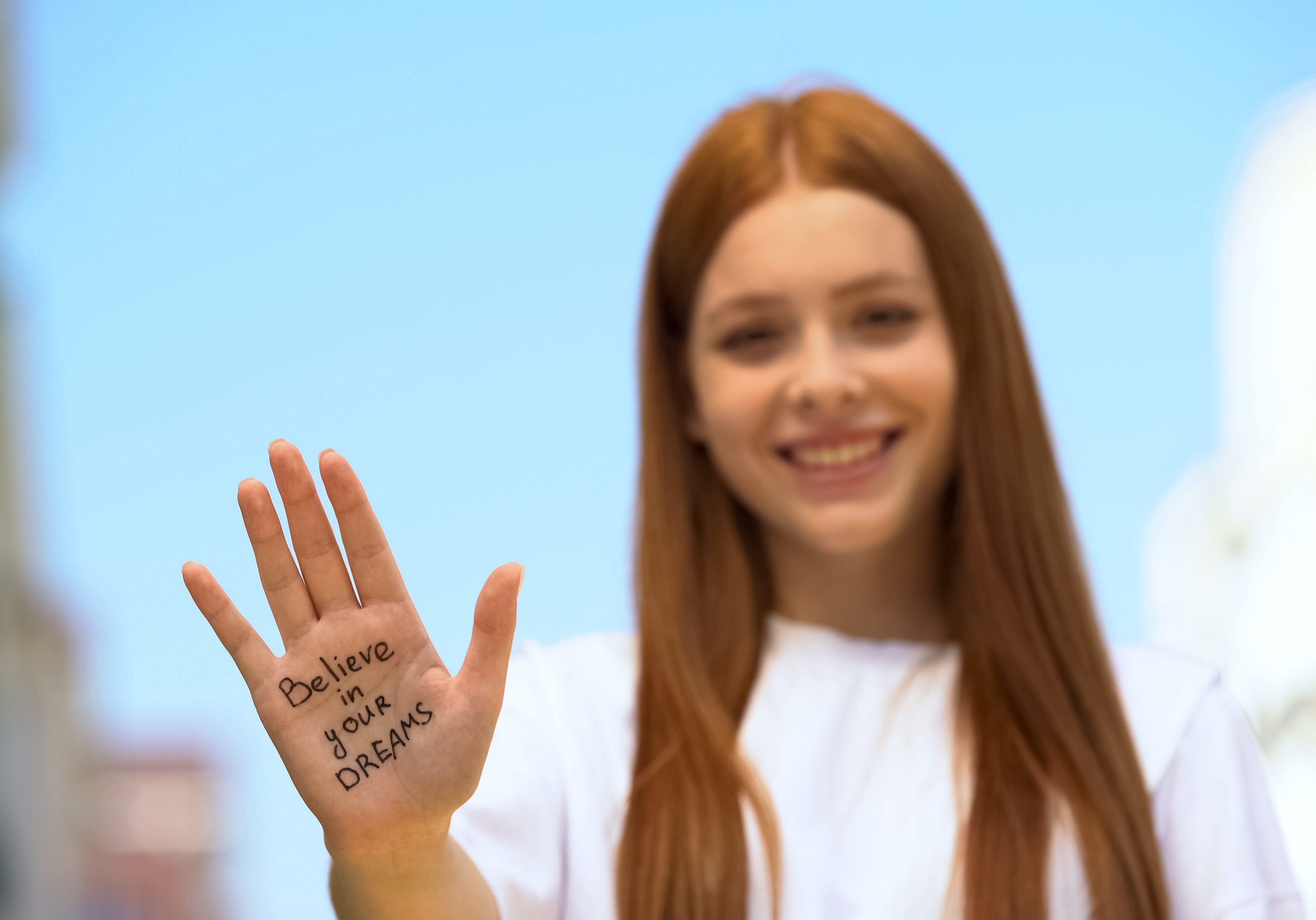 Smiling woman holds up hand with motivational message written on palm.