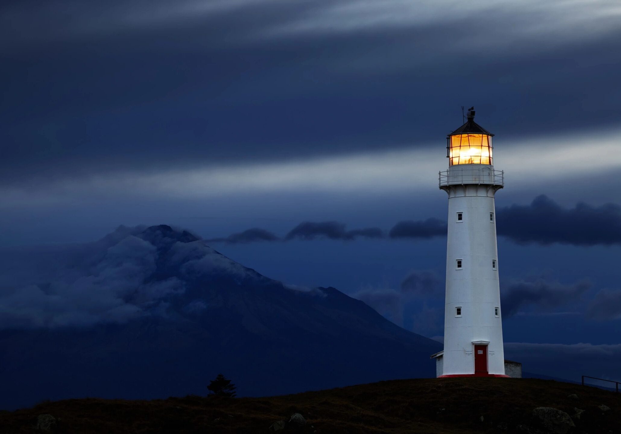 A lighthouse shining brightly against a dark, cloudy sky.